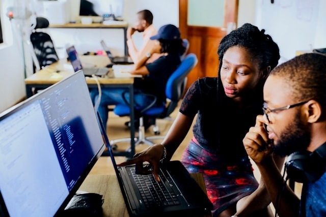 Team members collaborating on laptops in a modern office workspace